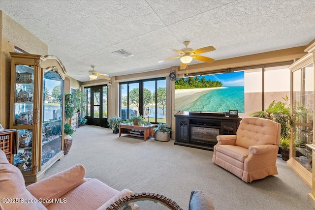 sunroom / solarium with a glass covered fireplace, visible vents, and ceiling fan