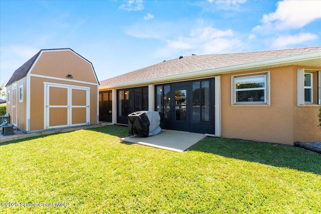 back of property with a sunroom, an outbuilding, a yard, a shed, and stucco siding