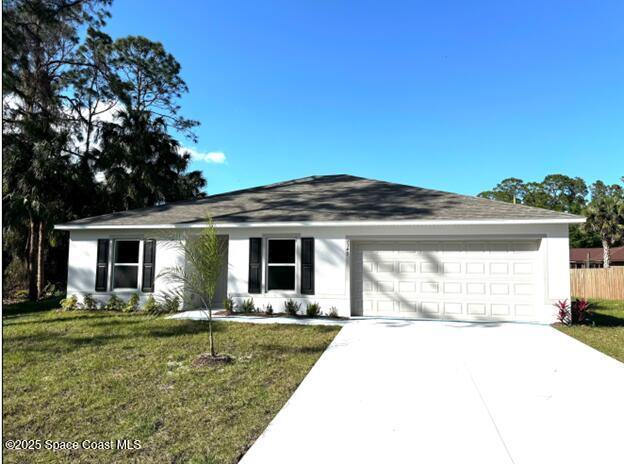 single story home with an attached garage, fence, concrete driveway, stucco siding, and a front yard