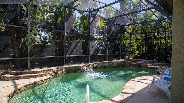 outdoor pool featuring glass enclosure and a patio