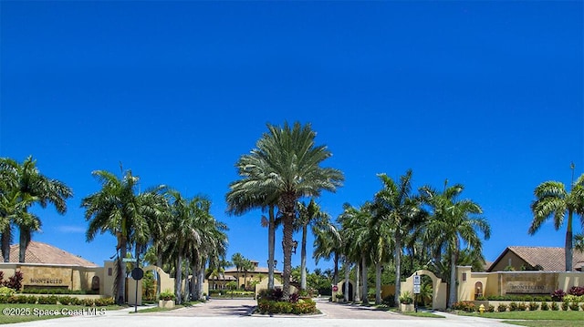 view of street featuring a residential view, a gated entry, curbs, traffic signs, and a gate