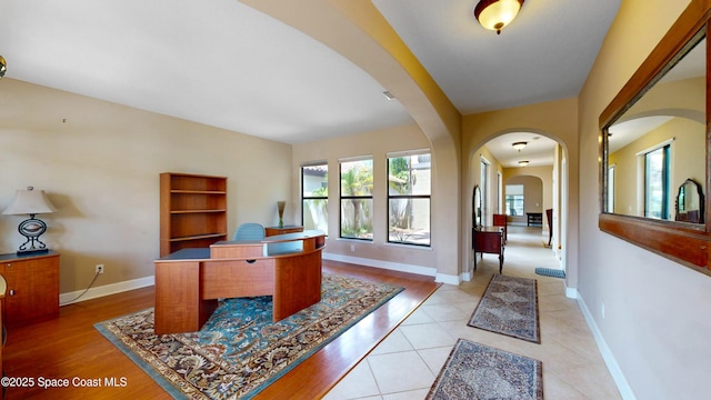 office featuring light tile patterned floors, baseboards, and arched walkways