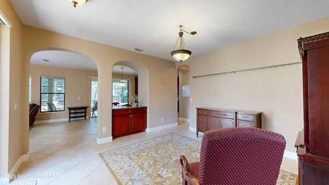 dining room with light tile patterned floors, arched walkways, visible vents, and baseboards