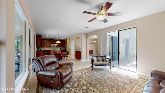 living area with arched walkways, light tile patterned floors, a wealth of natural light, and baseboards