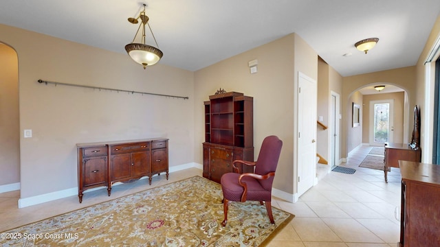 sitting room with stairway, baseboards, arched walkways, and light tile patterned flooring