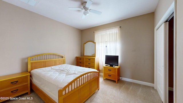 bedroom with a closet, light colored carpet, ceiling fan, and baseboards