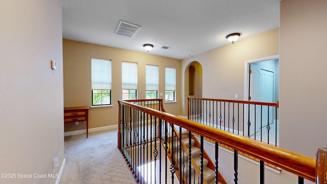 corridor with carpet floors, visible vents, and baseboards