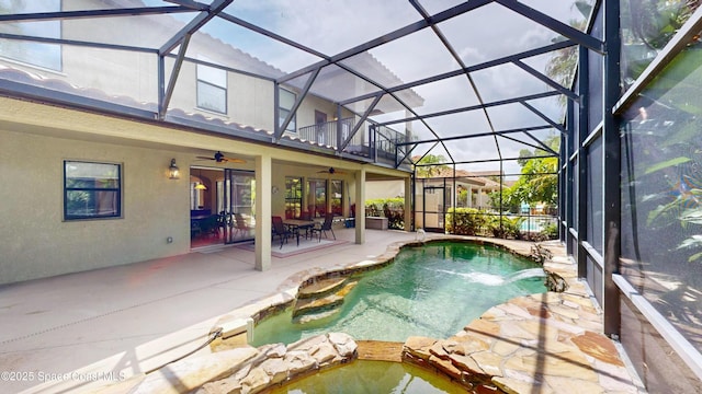 outdoor pool featuring a ceiling fan, glass enclosure, and a patio area