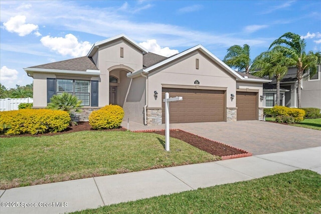 ranch-style house with decorative driveway, stone siding, an attached garage, and stucco siding