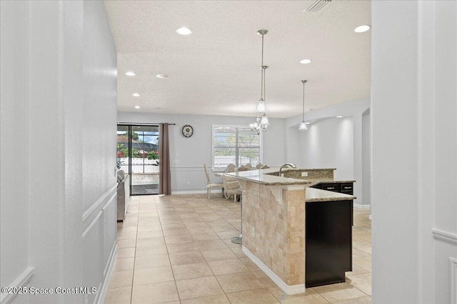 kitchen featuring light stone counters, light tile patterned flooring, a sink, and recessed lighting