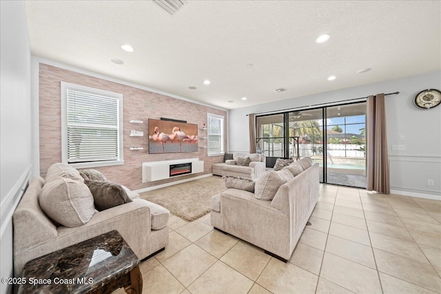 living room featuring a healthy amount of sunlight, light tile patterned floors, and a glass covered fireplace