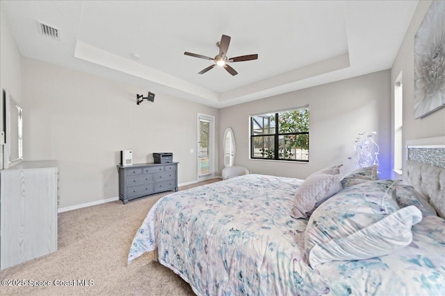 bedroom featuring carpet floors, a raised ceiling, visible vents, and baseboards