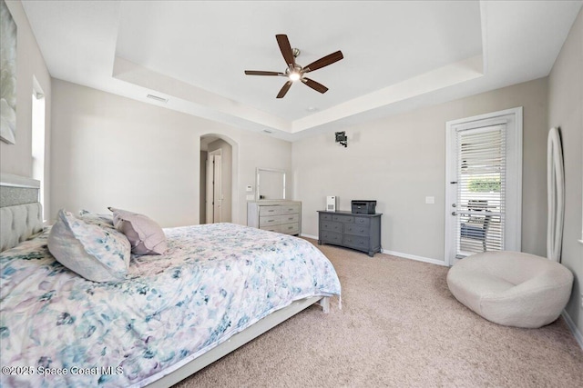 bedroom with visible vents, arched walkways, a raised ceiling, baseboards, and light colored carpet