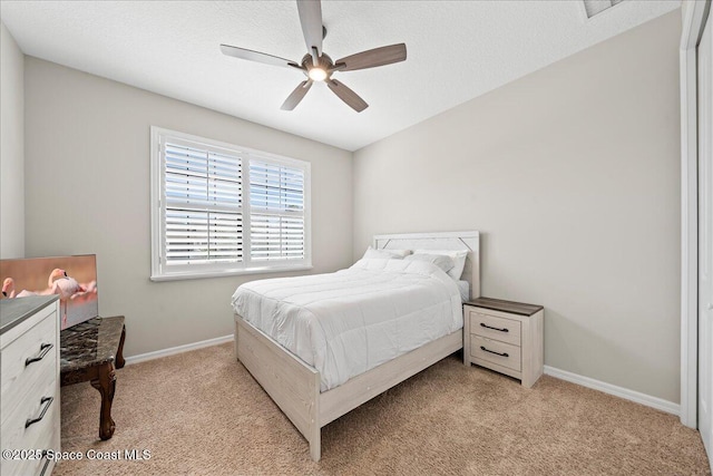 bedroom featuring light carpet, a textured ceiling, a ceiling fan, and baseboards