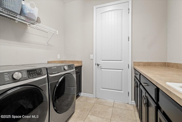 washroom with washer and clothes dryer, light tile patterned flooring, and cabinet space