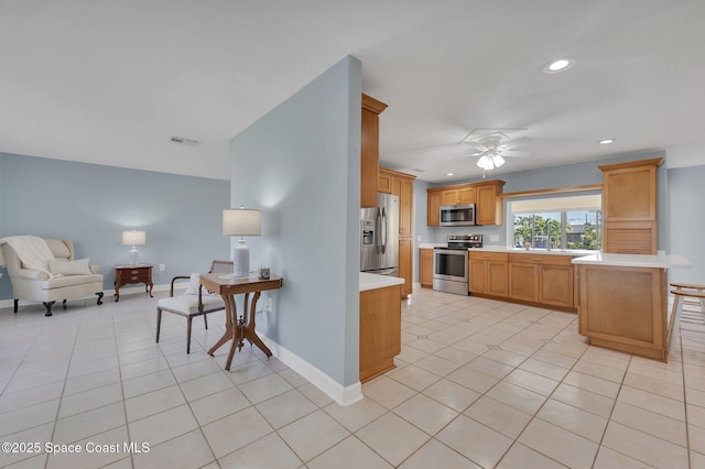 kitchen with light tile patterned floors, baseboards, stainless steel appliances, light countertops, and open floor plan