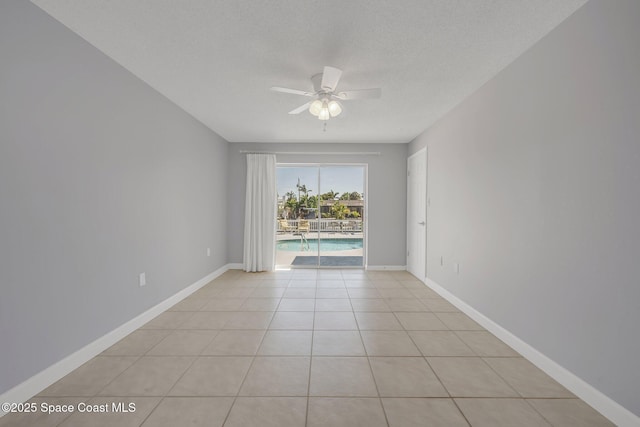 unfurnished room with baseboards, light tile patterned floors, a textured ceiling, and ceiling fan