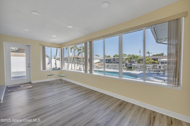 unfurnished sunroom featuring baseboards and wood finished floors