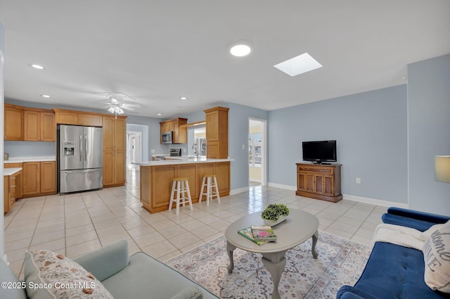 living area with a skylight, light tile patterned flooring, recessed lighting, and baseboards