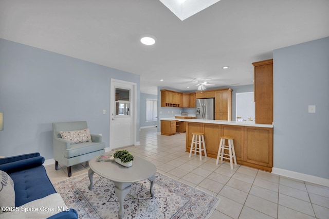 living area featuring ceiling fan, baseboards, light tile patterned floors, recessed lighting, and a skylight