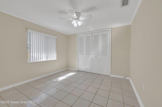 unfurnished bedroom with visible vents, ceiling fan, baseboards, light tile patterned flooring, and a closet