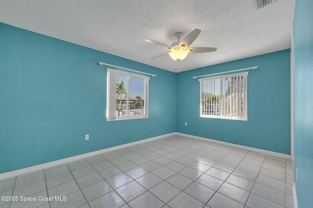 spare room featuring tile patterned floors, visible vents, a textured ceiling, baseboards, and ceiling fan