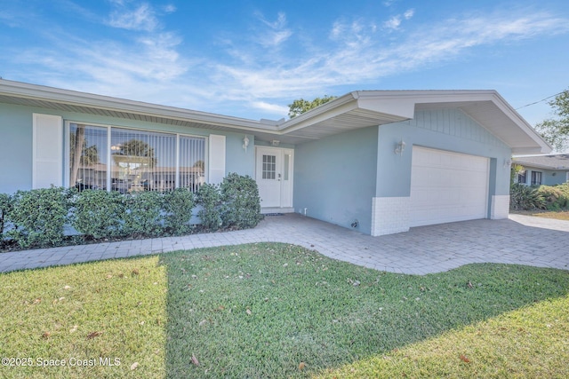 ranch-style home featuring stucco siding, a front yard, decorative driveway, and a garage