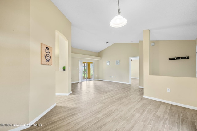 spare room with light wood-style floors, visible vents, vaulted ceiling, and baseboards