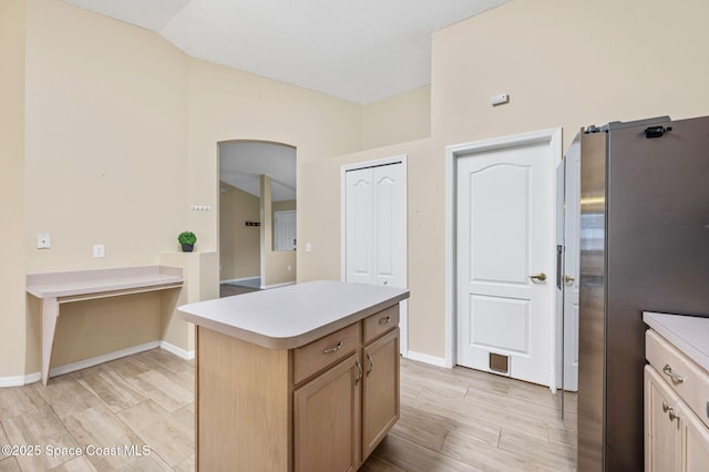 kitchen featuring wood tiled floor, arched walkways, light countertops, and freestanding refrigerator