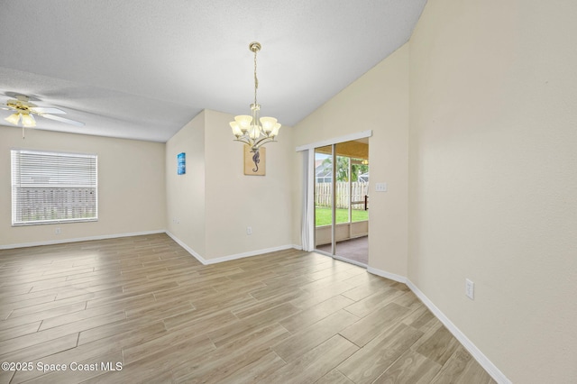 unfurnished room with lofted ceiling, a textured ceiling, light wood-type flooring, baseboards, and ceiling fan with notable chandelier