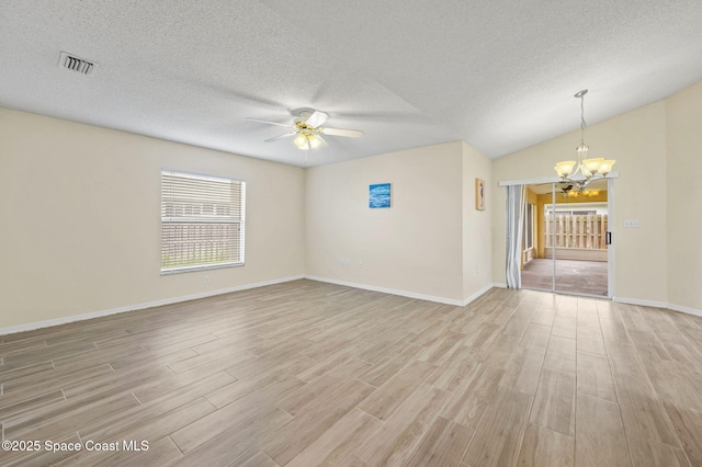 empty room featuring ceiling fan with notable chandelier, a textured ceiling, light wood-type flooring, and visible vents