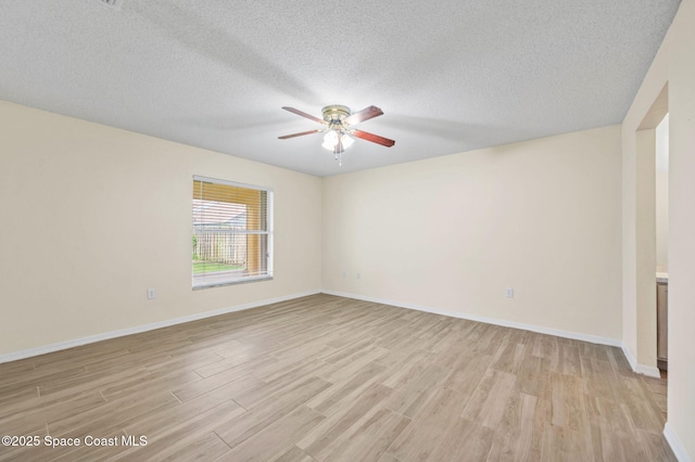 empty room featuring baseboards, ceiling fan, a textured ceiling, and light wood finished floors