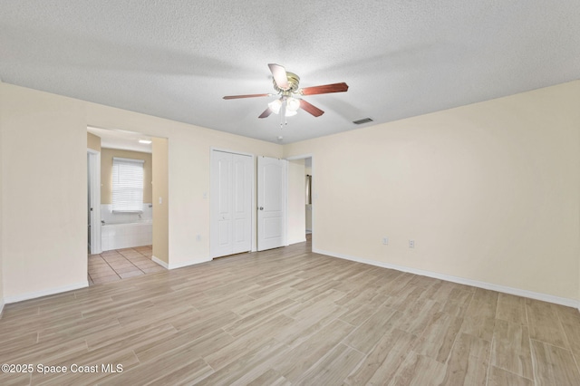 unfurnished bedroom featuring visible vents, a textured ceiling, connected bathroom, and light wood-style flooring