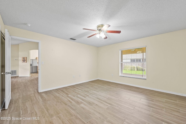 spare room featuring baseboards, light wood-style flooring, visible vents, and a ceiling fan