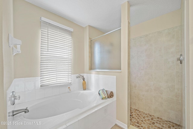 bathroom featuring a garden tub, a shower stall, and a textured ceiling