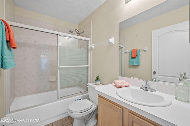 full bath featuring a textured ceiling, tile patterned flooring, toilet, bath / shower combo with glass door, and vanity