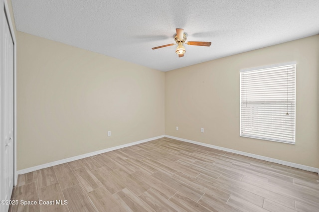 unfurnished room with ceiling fan, a textured ceiling, baseboards, and light wood-style floors