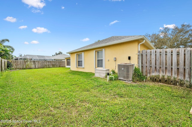 back of property featuring central AC, a yard, a fenced backyard, and stucco siding