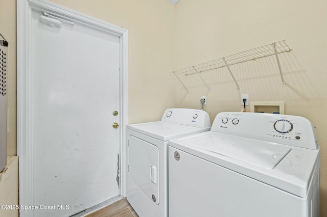 clothes washing area featuring laundry area, light wood-style flooring, and washing machine and clothes dryer