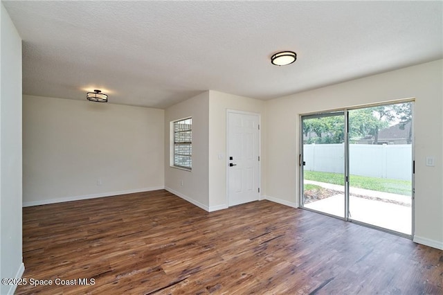 interior space with baseboards, dark wood-type flooring, and a textured ceiling