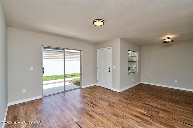 spare room with a textured ceiling, baseboards, and wood finished floors