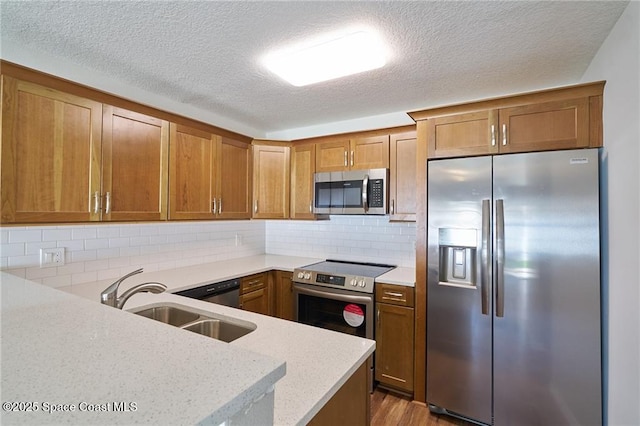 kitchen featuring brown cabinets, stainless steel appliances, and a sink