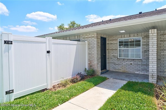 doorway to property with a gate, fence, and brick siding