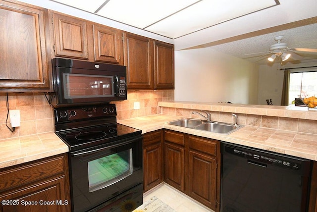 kitchen with a peninsula, a sink, a ceiling fan, backsplash, and black appliances