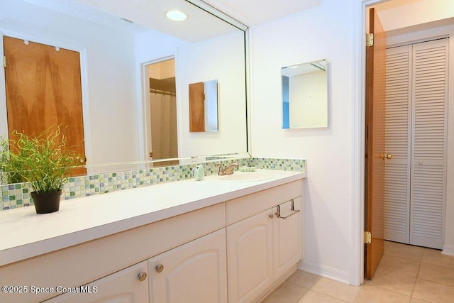 bathroom with a closet, tile patterned flooring, vanity, and decorative backsplash