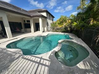 view of swimming pool with fence, a pool with connected hot tub, and a patio area