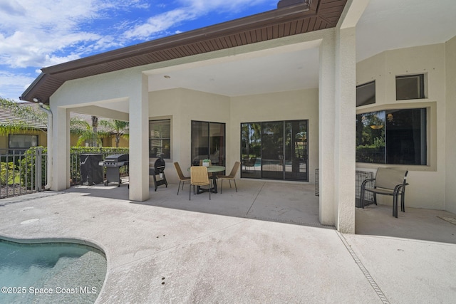 view of patio / terrace featuring an outdoor pool, area for grilling, fence, and outdoor dining space