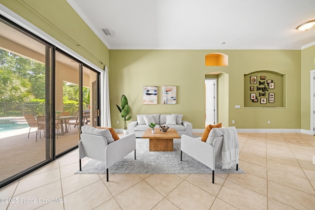 tiled living room with arched walkways, crown molding, baseboards, and visible vents