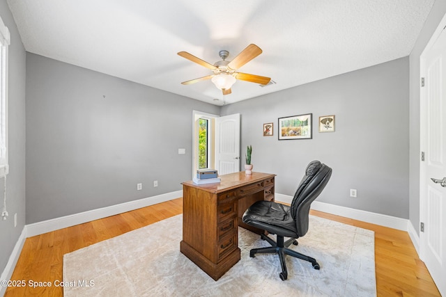 home office with baseboards, light wood-style flooring, and a ceiling fan
