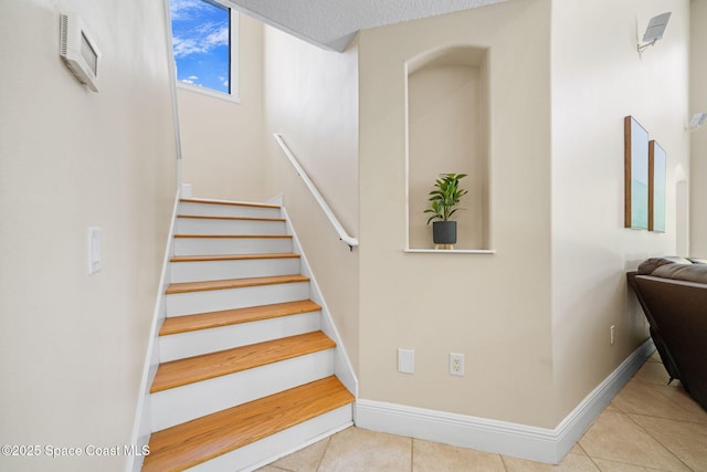 stairway featuring baseboards, a textured ceiling, and tile patterned floors